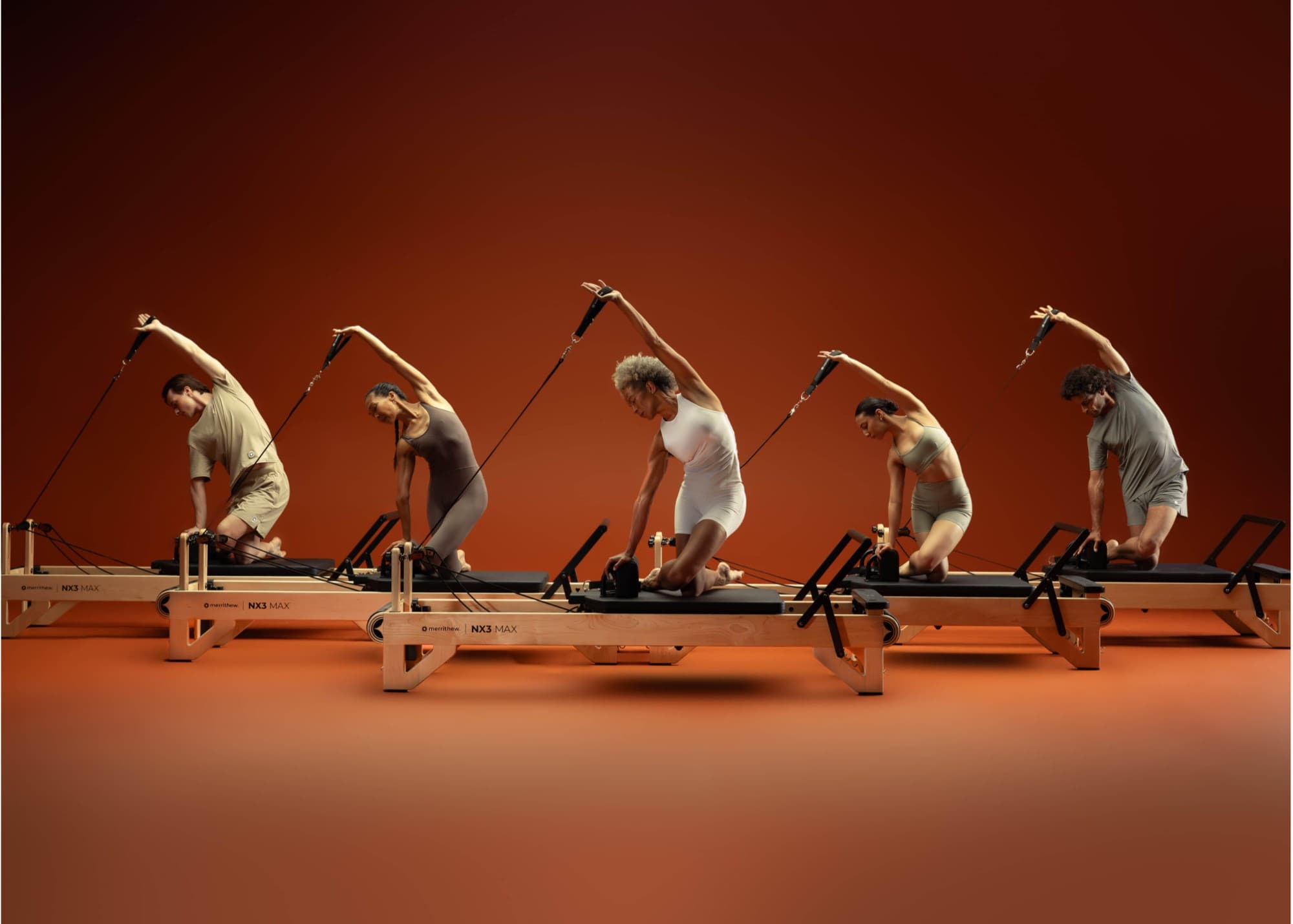 Group class performing mermaid stretch on five NX3 MAX reformers