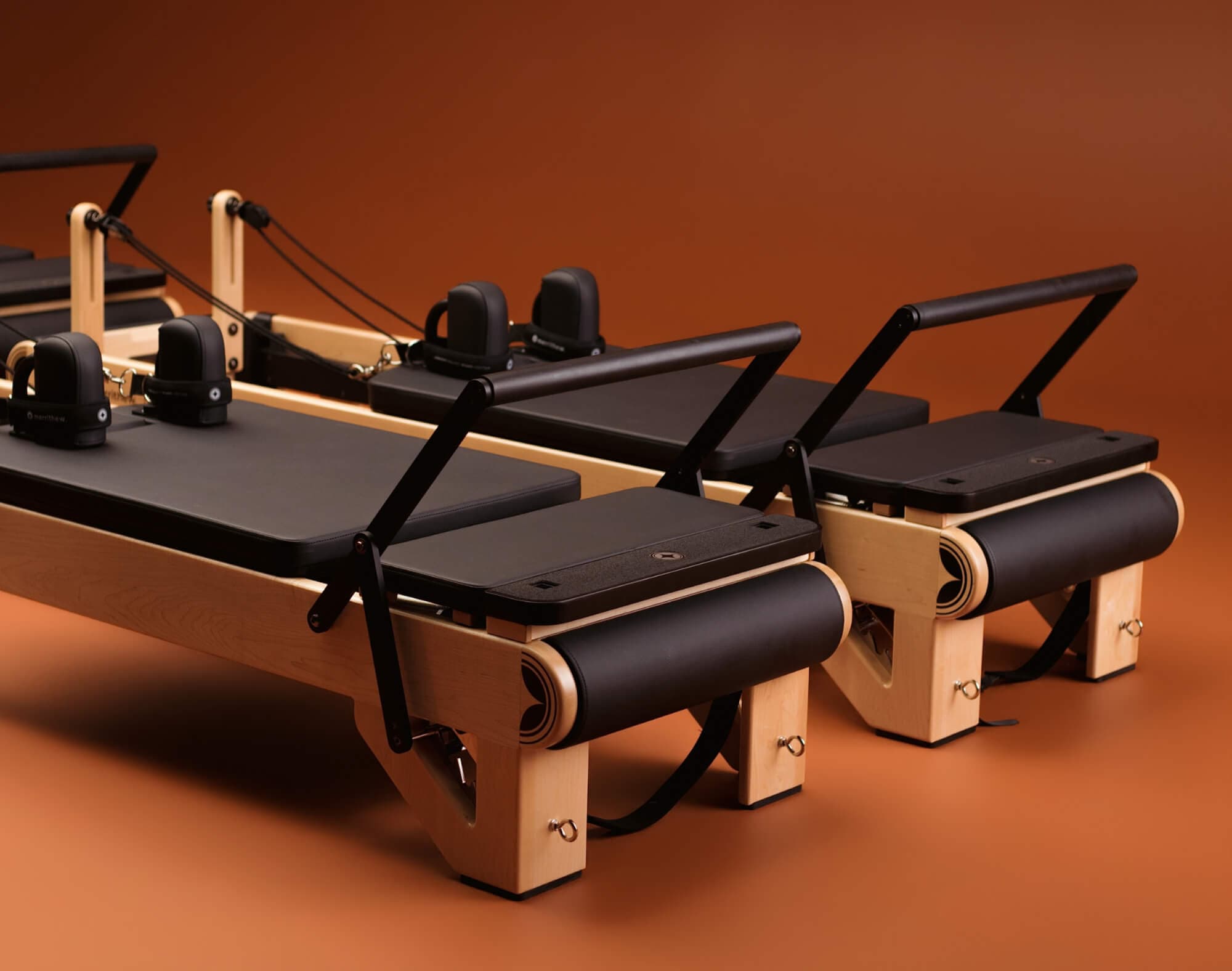 Padded platforms, footbar and shoulder rests on two NX3 MAX reformers